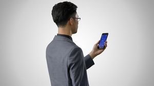 4k灰底抠像合成商务男性使用蓝幕手机背影19秒视频