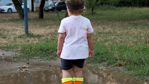 穿着橙色靴子的幼儿在雨后穿过水坑21秒视频