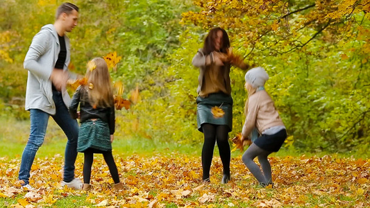 在秋天户外放风时年轻笑着微笑的家庭扔树叶视频