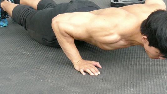 年轻的肌肉男在健身房做平板支撑健美男在健身中心锻炼视频