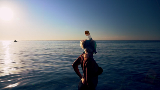 身穿潜水衣的妇女进入平静的海面视频