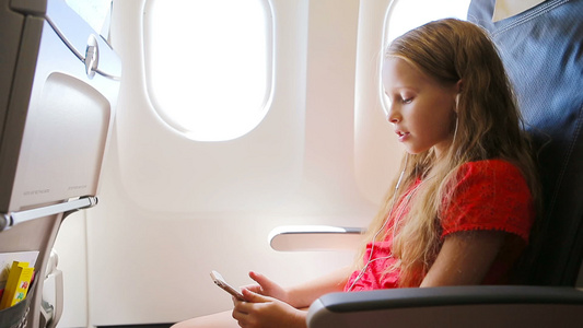 乘飞机旅行的可爱的小女孩坐在窗边坐在飞机窗口附近的视频