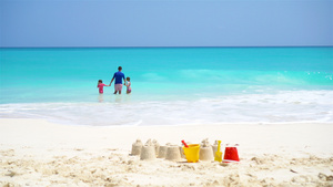 白沙滩上的沙堡有塑料小孩玩具和家庭在海背景中25秒视频