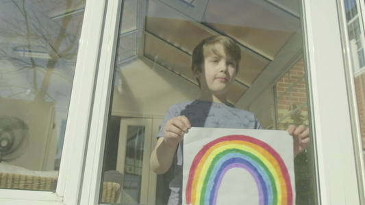 男孩将彩虹的图像贴在窗口上视频