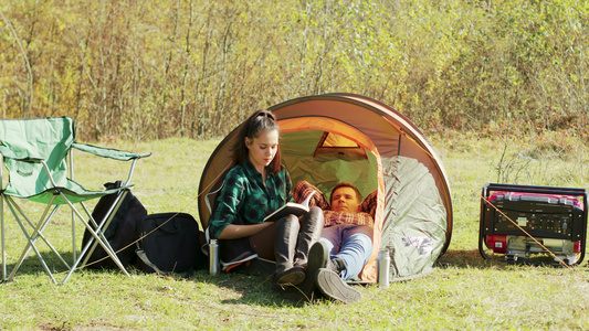 男朋友在露营帐篷上躺下而女友在看书视频