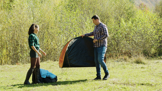 具有吸引力的年轻男子及其女友为露营搭建帐篷视频