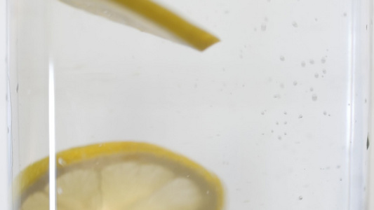 慢动作柠檬溅入有气泡的水中冷鲜鸡尾酒加柠檬健康生活视频