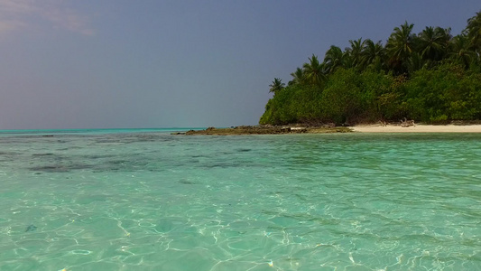 靠近礁石的干净沙滩背景的蓝海豪华度假村海滩度假的广角视频