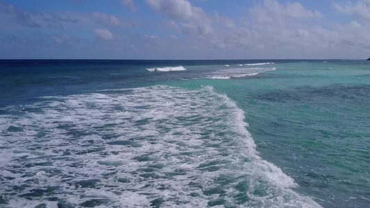 沿蓝海和靠近度假胜地的白沙背景航行的豪华海岸海滩宽角视频