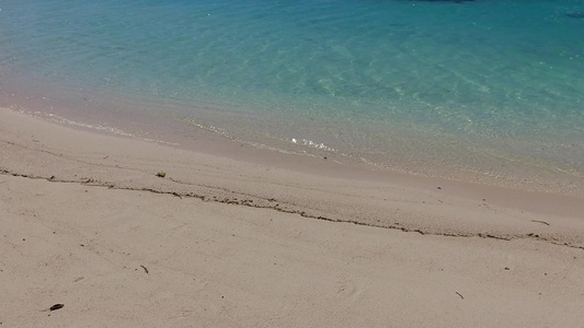 蓝色的海洋和礁石附近的白色沙滩背景完美的海滨海滩度假视频