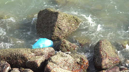 岩石上丢弃的塑料袋流视频