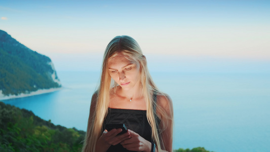 金发女金发使用智能手机与海洋背景视频