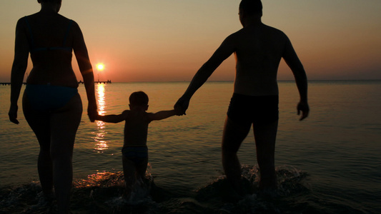 日落时父母和儿子在海上玩球视频