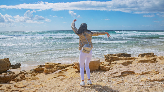 年轻女子在风中跳舞在暴风海的岸边视频