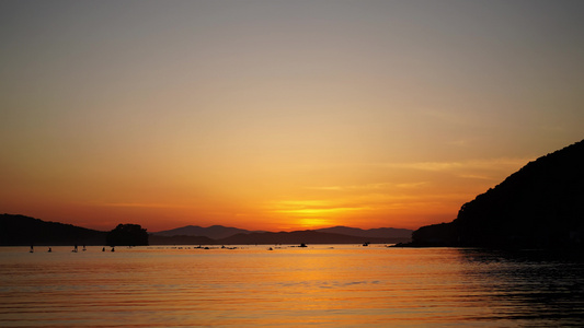 日落时海景与冲浪者在黄昏时的漫步视频