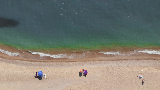 无法辨认的人在美丽的绿松石蓝色海滩顶部空中角度晒日光浴视频