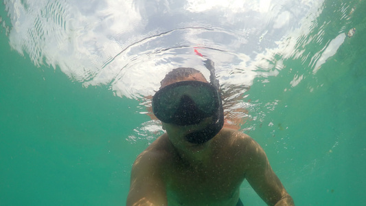 戴面罩在海上潜水手挥着相机的滑行男子视频