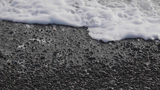 海浪和泡沫正在滚动在鹅卵石海岸上超慢运动近视视频