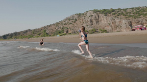 慢动作快乐的女孩在绿色高地景观的海水上奔跑快乐的少年8秒视频
