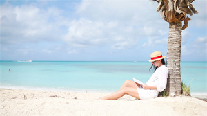 热带白沙滩上年轻女子阅读书24秒视频