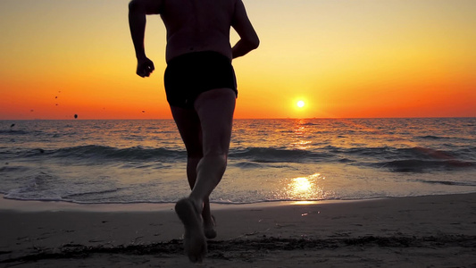 人类奔跑跳进海水的日落水中随着喷发慢动作视频