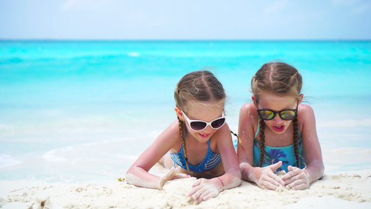 可爱的小孩在白沙滩上玩沙子两个女孩暑假时玩得开心视频
