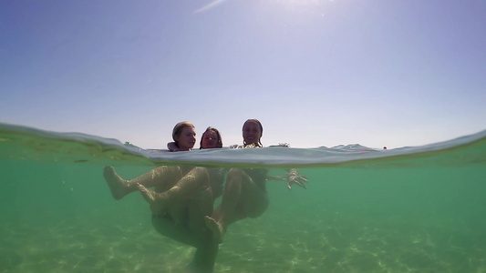 一群三个十几岁的女孩在海边的水里玩得开心拥抱和喷溅视频