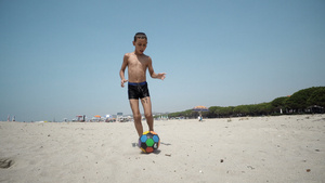 年轻男孩在空沙滩上玩踢球19秒视频