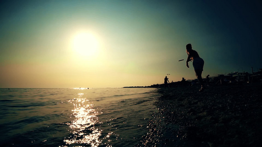 日出或日落时在海滩玩飞盘的休眠朋友慢动作视频