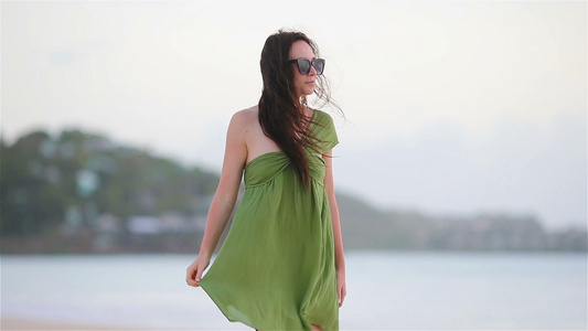 热带海岸的年轻美女在沙滩上绿德蕾丝的旅游女游客视频