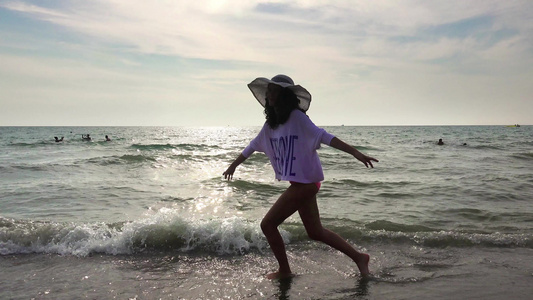 快乐的女孩享受散步的海滩双臂自由伸展跳跃被海浪溅起视频