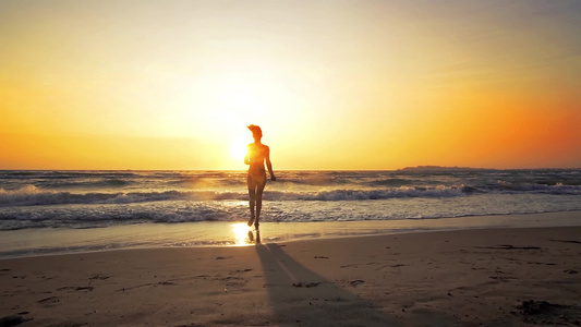 完美身材性感的性感女人在日落时在沙滩上奔跑跳入海水视频
