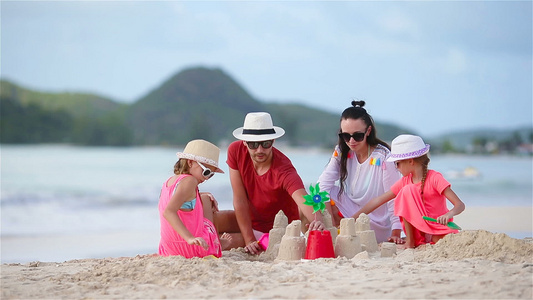 家庭在热带白色海滩建造沙滩城堡视频