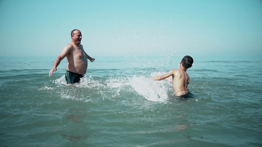 快乐的家庭在海滩上玩得开心慢慢地在海水中泼水视频