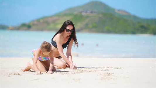在白沙沙滩上享受家庭乐趣母亲和小孩享受暑假视频