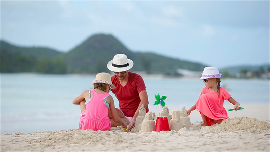 父亲和小孩在热带海滩建沙滩的沙城堡视频