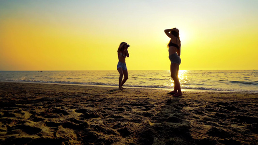 日落时在海滩拍摄女性模特的照片的青少年摄影师浪漫照片视频