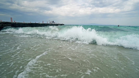海滩上的海浪破碎背景有码头视频