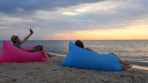 一对夫妇在日出时坐在沙滩上的充气沙发上年轻人在海滩17秒视频