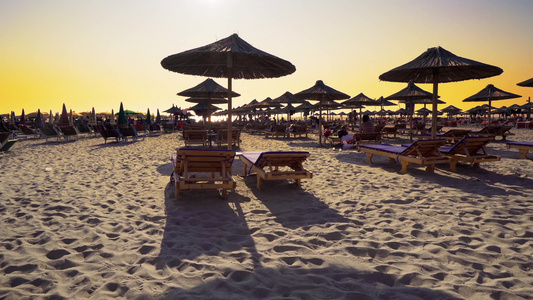 日落时在海滩上挂着雨伞的沙滩椅视频