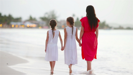 可爱的小女孩和年轻母亲在白沙滩上视频