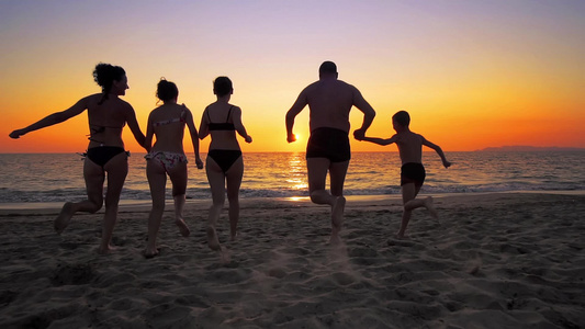 一群快乐的人在日落时在海滩上玩耍和喷水美丽和快乐的视频
