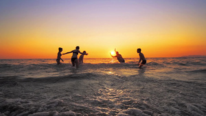 在日落时一群快乐的人在海滩上玩耍30秒视频