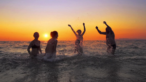 在日落时一群快乐的人在海滩上玩耍30秒视频