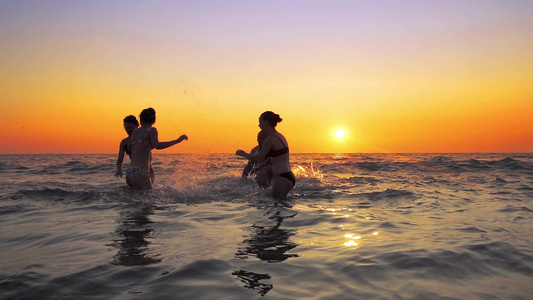 在海滩日落慢动作时人们跳舞和喷洒的青年欢乐派对视频