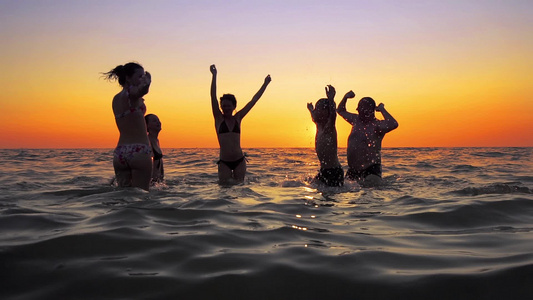 在海滩日落慢动作时人们跳舞和喷洒的青年欢乐派对视频