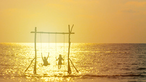 4K幸福的夫妇的剪影喜欢在日落时分在海面上荡秋千在20秒视频