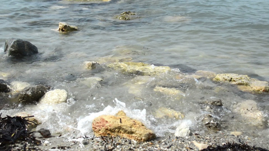 白色沙滩岸边岩石上的小海浪相近视频