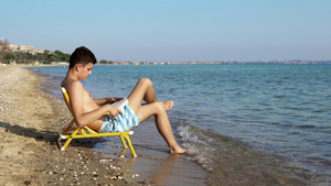 年轻男子在海滩上读一本书19秒视频