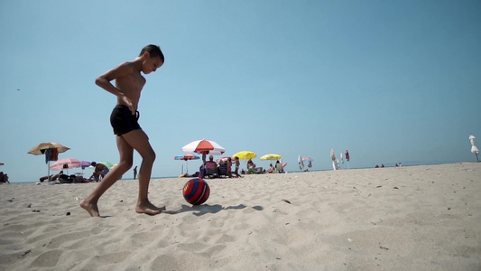 快乐的男孩玩得开心在海滩踢足球慢动作视频